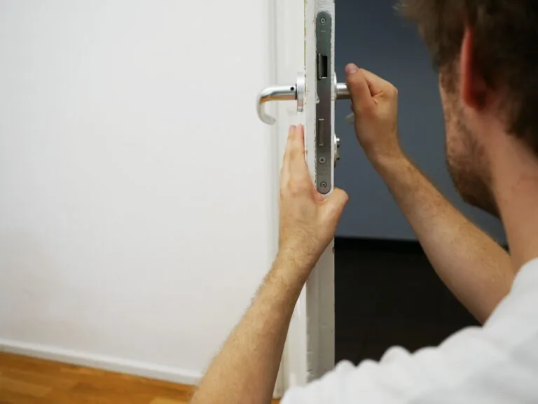 Slotenmaker werkt aan het insteekslot in de rand van een witte deur