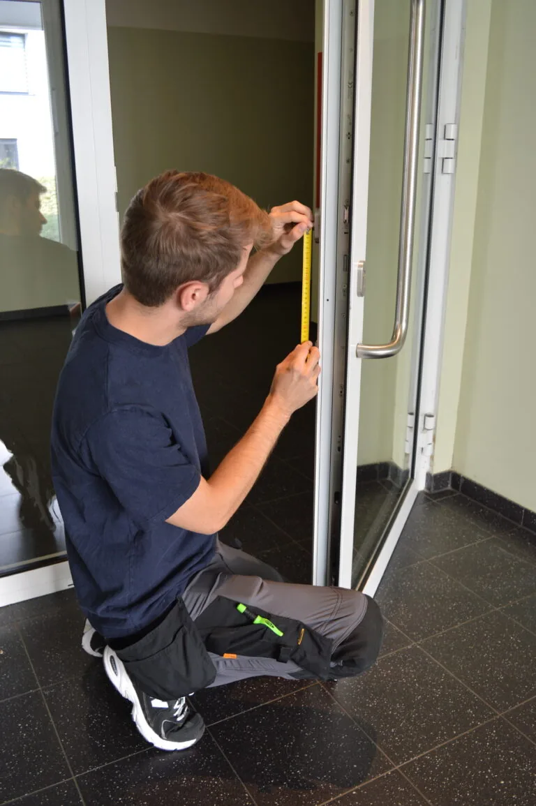 Slotenmaker meet een glazen toegangsdeur op met een duimstok